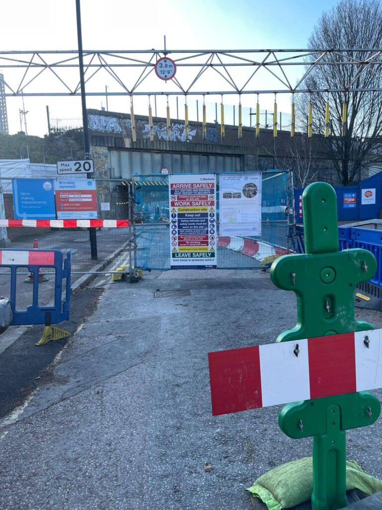 HERAS wire fencing obscuring a part of a carriageway before a low bridge. A poster on the fencing says "26th Janauary 2026 to Autumn 2028".
