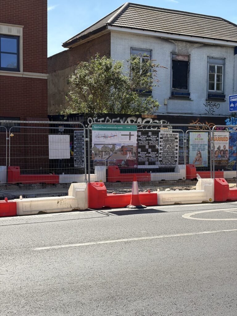 Across the street, fencing surrounds a cycle track under construction. A poster board attached to the fencing shows a map of the scheme and the design for Green Street junction, complete with a visualisation.