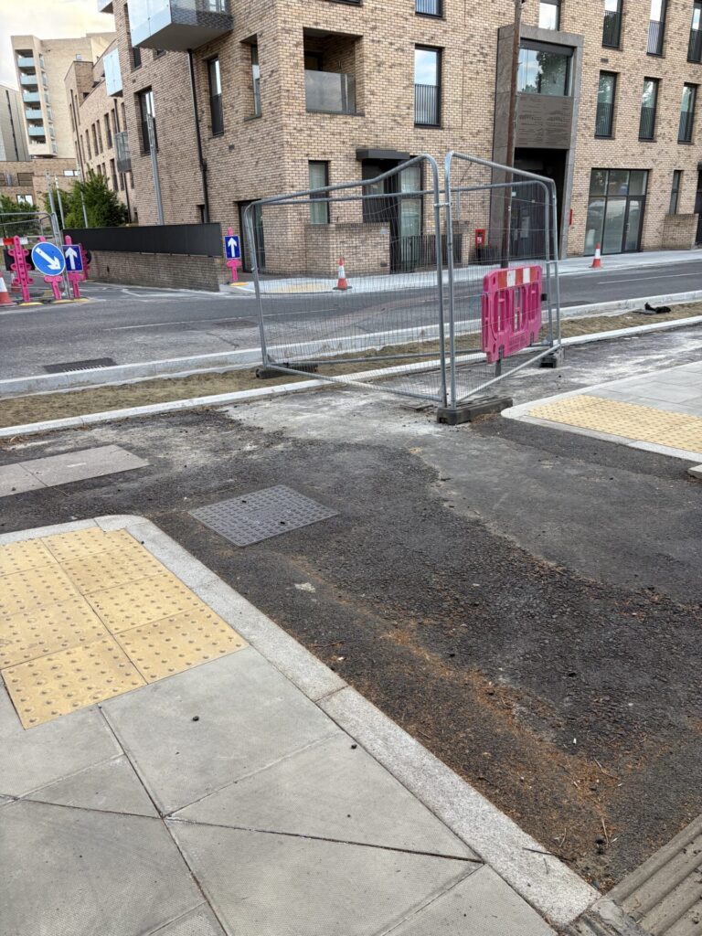 Unfinished two-way cycle track with a connection to a side street. Crossing of connection uses buff rectangular tactiles.